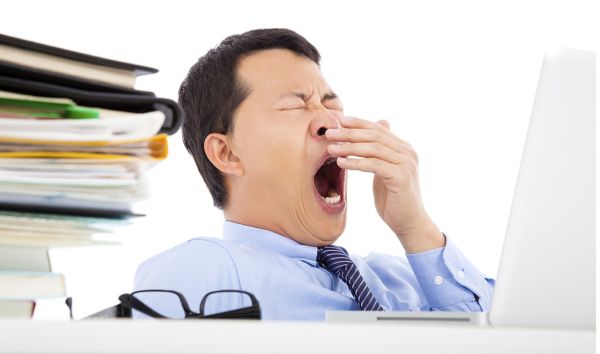 Exhausted young businessman yawning at work